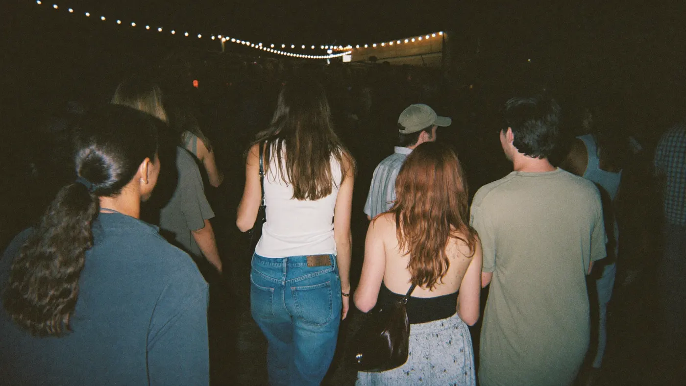 Friends walking into a night market under string lights